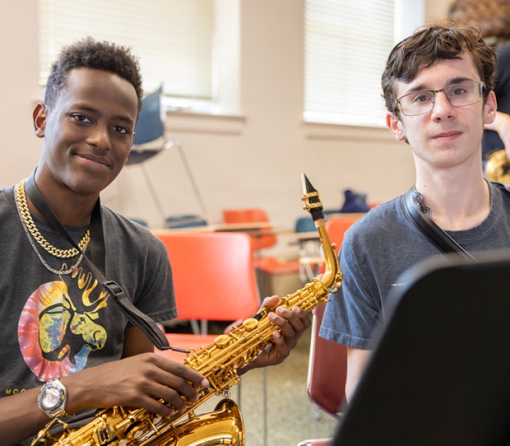 Two students holding saxaphones and smiling at the camera
